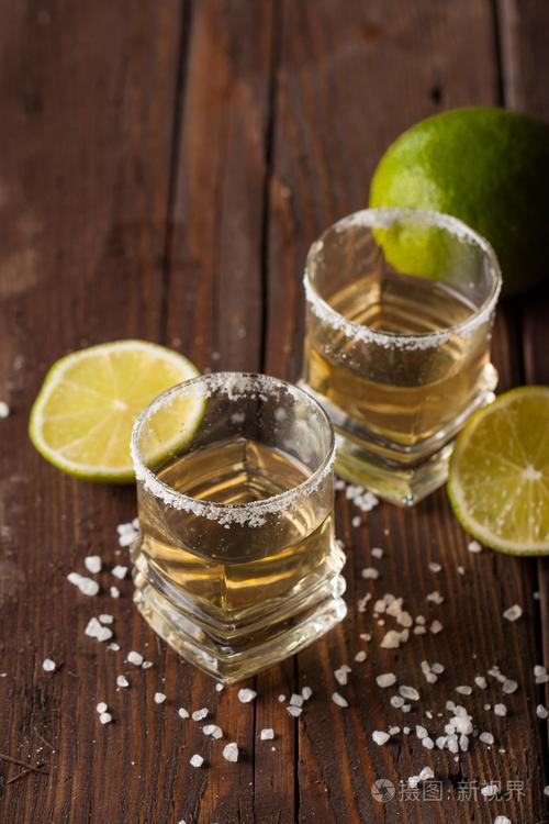 宏观焦点照片的黄金墨西哥龙舌兰与石灰和盐在木制背景酒精饮料的概念